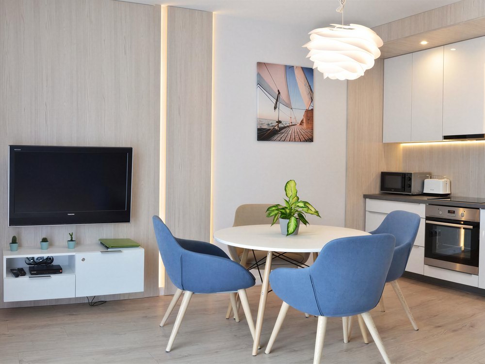 Apartament Woda – salon z aneksem kuchennym i niebieskimi krzesłami